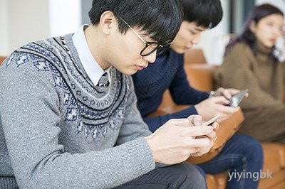 几个人坐在一起玩手机，www.yiyingbk.com